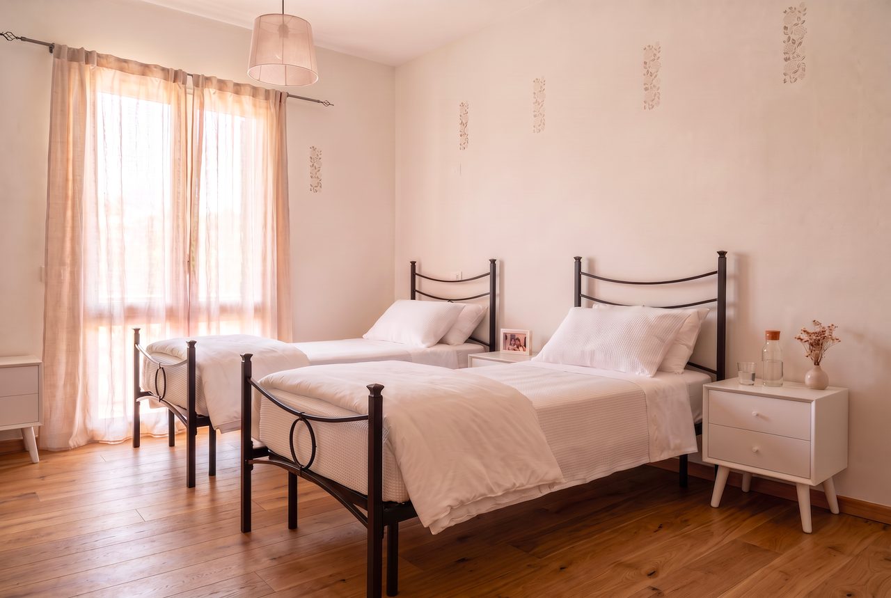 Camera da letto di Residenza Althea: due letti singoli, comodino e luce naturale dalla finestra.